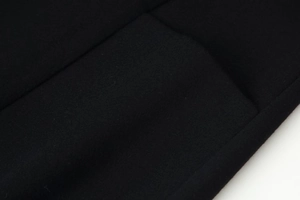 Gros plan sur la texture du tissu en laine noire et les détails de couture de la robe
