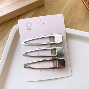 Close-up of three silver Y2K metal hair clips on a pink card with a smooth finish