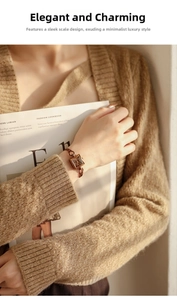Elegant rose gold square watch with twisted chain strap on model's wrist with magazine