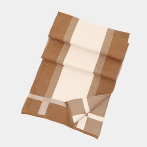 Detail view of thick knitted winter scarf featuring brown and beige color block pattern