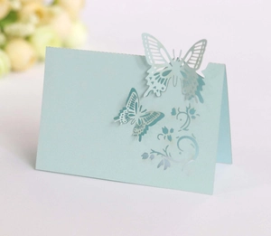 Detail of laser-cut light blue butterfly place card with intricate floral patterns