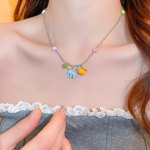 Close-up of beaded necklace with blue elephant and flower pendants worn by a model