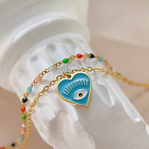 Macro shot of gold-plated chain with blue enamel heart and evil eye charm detail