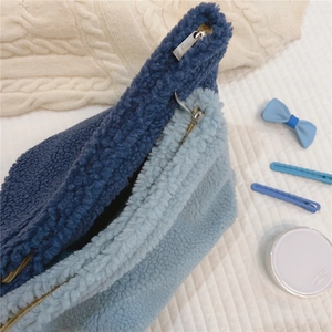 Detail of blue sherpa fleece cosmetic bag showing soft texture and metal zipper