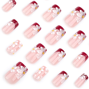 Floral French press-on nails with red tips and white daisy art on a pink base