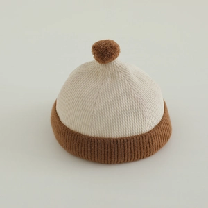 Detail of baby knitted beanie with pompom showing fine ribbed texture and soft fabric