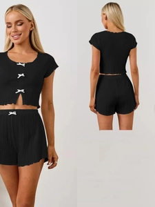 Détail de l'ensemble de détente noir en tricot côtelé avec nœuds blancs et bord ondulé
