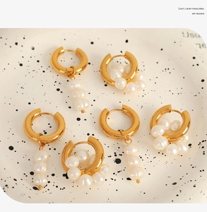 Trois paires de boucles d'oreilles anneaux dorés asymétriques avec perles sur plat céramique
