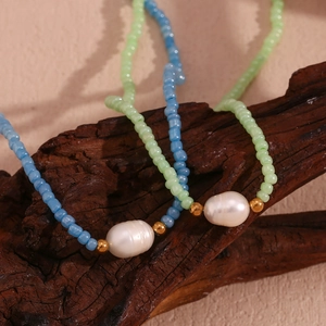 Detailed close-up of colorful seed bead necklaces with freshwater pearls on dark wood