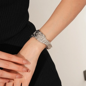 Dettaglio di un ampio bracciale a polsino in argento con trama stropicciata irregolare