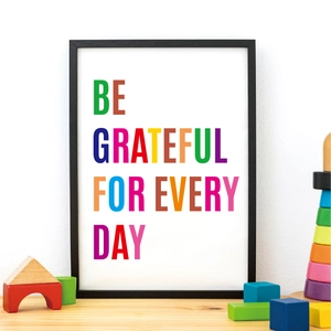 Close-up of framed inspirational poster 'Be Grateful For Every Day' on white wall with blocks