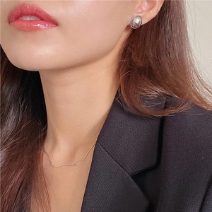 Detail of vintage silver mirror stud earrings and slim chain necklace on a model