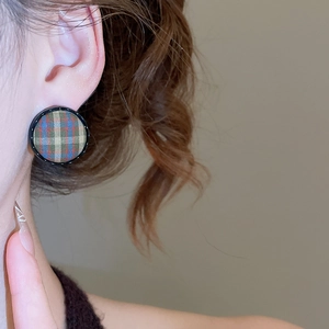 Macro shot of circular plaid fabric earrings with retro checked pattern and black rim