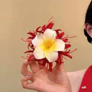 Nahaufnahme einer handgefertigten Stoff-Haarklammer mit Plumeria und roten Akzenten