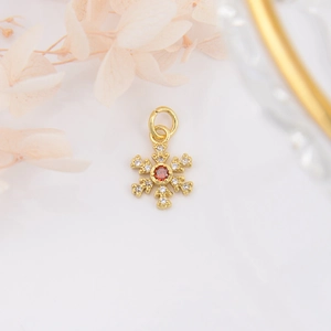 Detailed macro view of 18k gold plated snowflake pendant with red zircon center and crystals