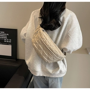 Rear view of a model wearing a beige quilted crossbody chest bag with adjustable strap