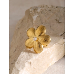 Close-up of 18k gold plated flower ring with sparkling zircon on a natural stone base