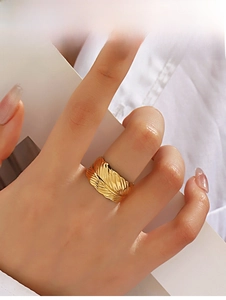 Detailed view of wide feather pattern ring in gold finish on finger