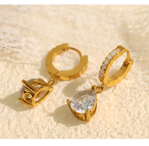 Vue macro de boucles d'oreilles dorées avec zircons et cristal en forme de goutte