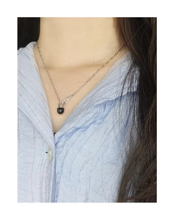 Close-up of S925 silver necklace with black agate pendant worn on a blue shirt