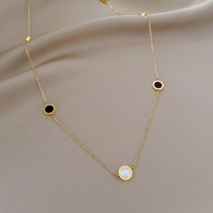Minimalist gold titanium necklace with black and white circular pendants on silk