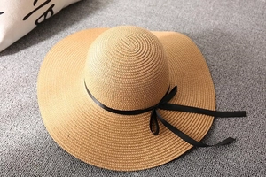 Close-up of wide-brim straw beach hat with black ribbon bow and fine weave texture