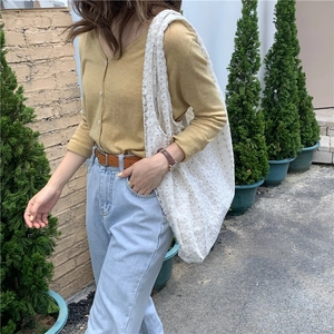Close-up of white lace canvas shoulder bag styled with yellow cardigan and blue jeans