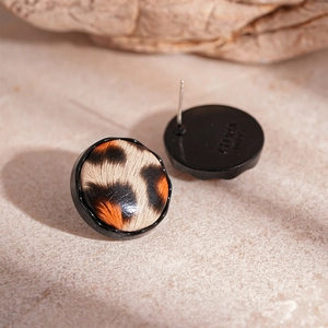 Detailed macro view of vintage leopard print round earrings on a rustic stone base