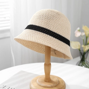 Detailed close-up of beige crochet bucket hat with black stripes on wooden stand
