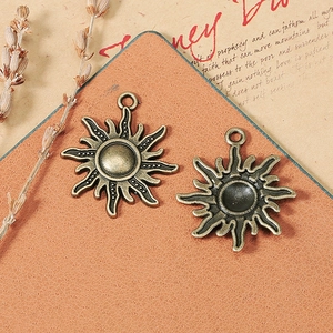 Vintage bronze sun charms for DIY jewelry making on orange textured mat with lavender decor