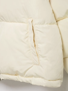 Detailed close-up of side pocket and smooth stitching on cream padded winter jacket