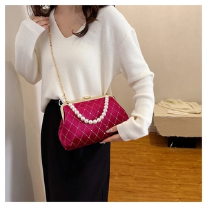 Detail of fuchsia velvet evening bag with quilted texture, pearls and gold chain