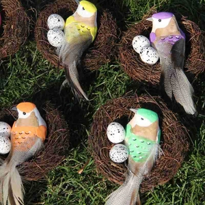 Nahaufnahme von künstlichen Vogelnestern mit bunten Vögeln und Eiern auf grünem Gras