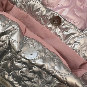 Dettaglio della borsa trapuntata argento con chiusura magnetica e fodera rosa