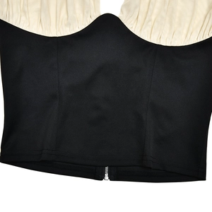 Detail of a color-block halter top featuring a black hem with a functional metal zipper
