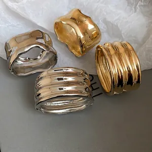 Irregular glossy metal oval cuff bracelet in gold and silver with fluid organic wave design