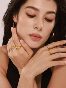 Polished gold twisted earrings and streamlined droplet rings worn on model closeup