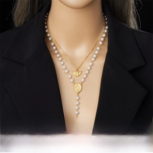 Detail of double-layer stainless steel necklace with angel pendant and pearl cross tassel