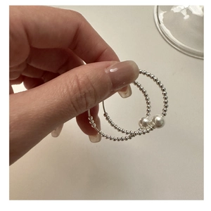 Handheld view of S925 sterling silver hoop earrings with delicate white pearls