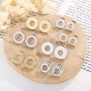 Detailed close-up of mixed gold and silver geometric circular stud earrings with zircons