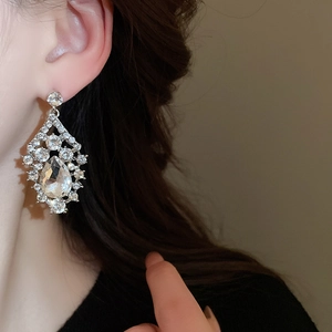 Close-up of silver teardrop earrings with crystals worn by a model in soft lighting