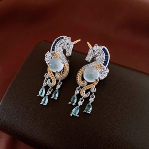 Detailed view of unicorn earrings with blue zircon tassels on leather background