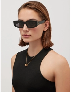 Detail view of bold black rectangular sunglasses with grey lenses and gold spiral pendant