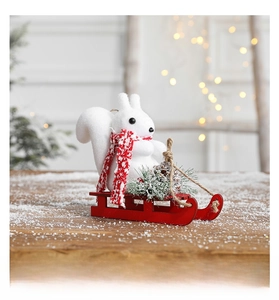 Detailed view of Christmas squirrel on a red wooden sleigh with mini pine cones