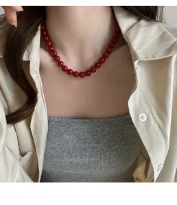 Détail d'un collier de perles en verre rouge vintage avec finition brillante sur un mannequin