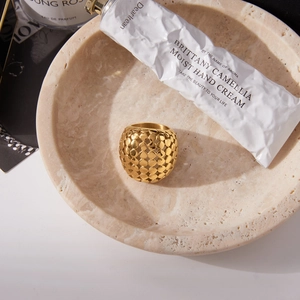 Détail d'une bague sphérique dorée ajourée sur un plateau en marbre avec accessoires de mode