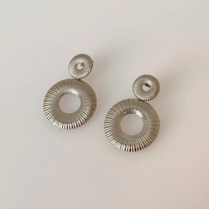 Detail of silver hoop earrings featuring artistic pleated texture and stacked double rings