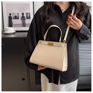 Detail view of a beige leather top handle bag with golden clasp and adjustable shoulder strap