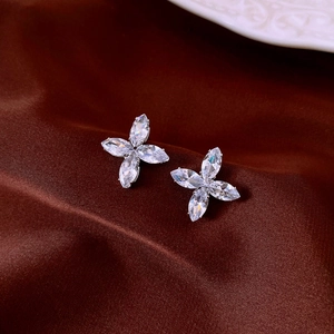 Macro shot of silver zircon flower stud earrings on dark brown silk background