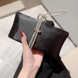 Close-up of elegant black satin evening clutch featuring luxury rhinestone braided handle